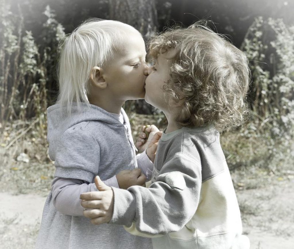 Маленькая девочка целуется с маленьким мальчиком